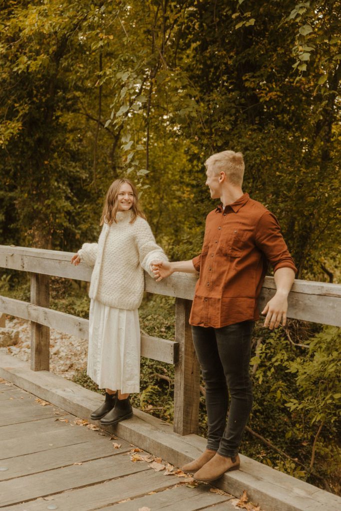 Newly engaged couple on the riverside bridge at finley farms in ozark missouri