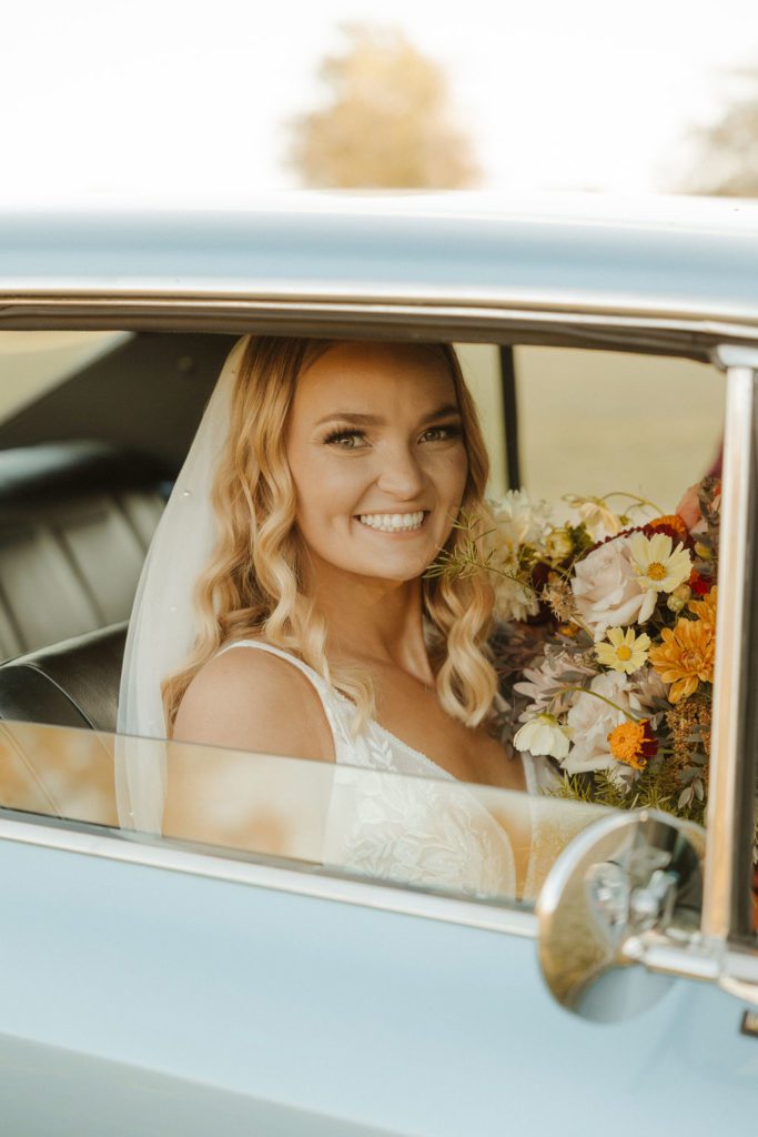 Bride posing with wedding boquet in vintage car in Mt Home Arkansas