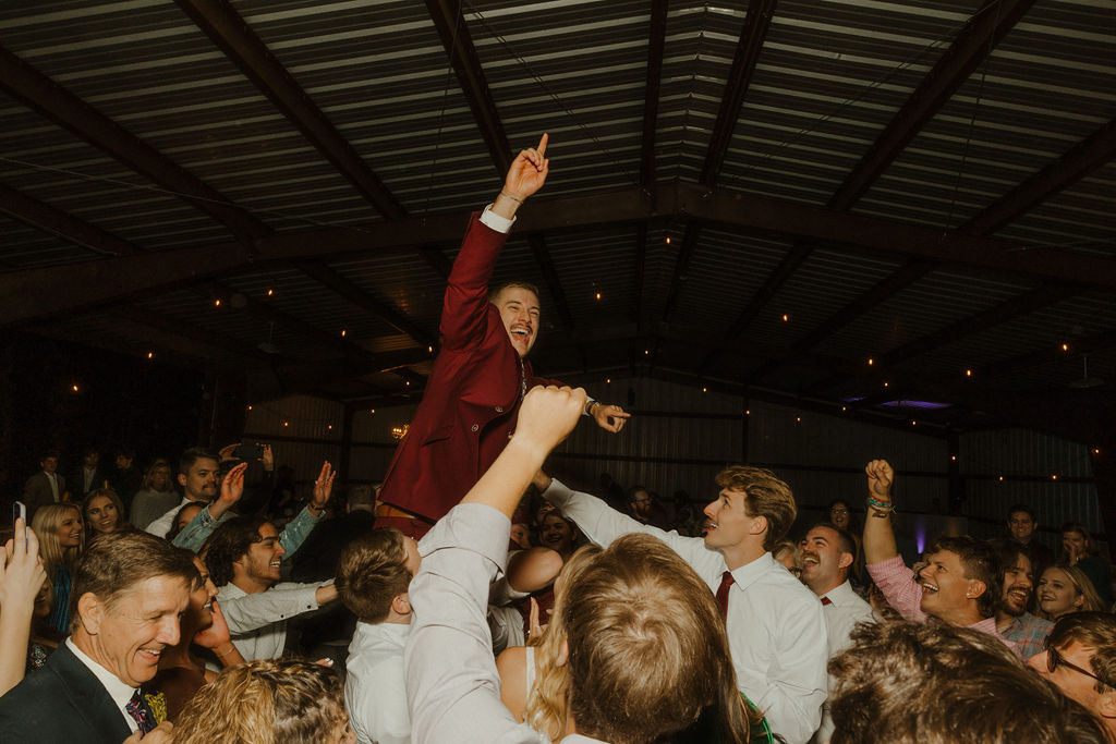 crowd picking up groom at wedding reception